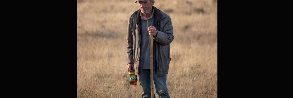 Romanian_shepherd_leaning_on-staff_in_the_countryside