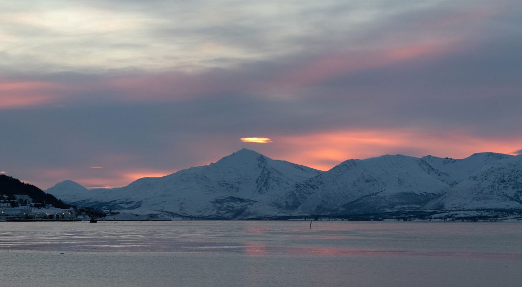 Sunset_over_the_Norwegian_mountains_illuminating_snow_capped_peaks_and_dramatic_clouds_above_the_fjord