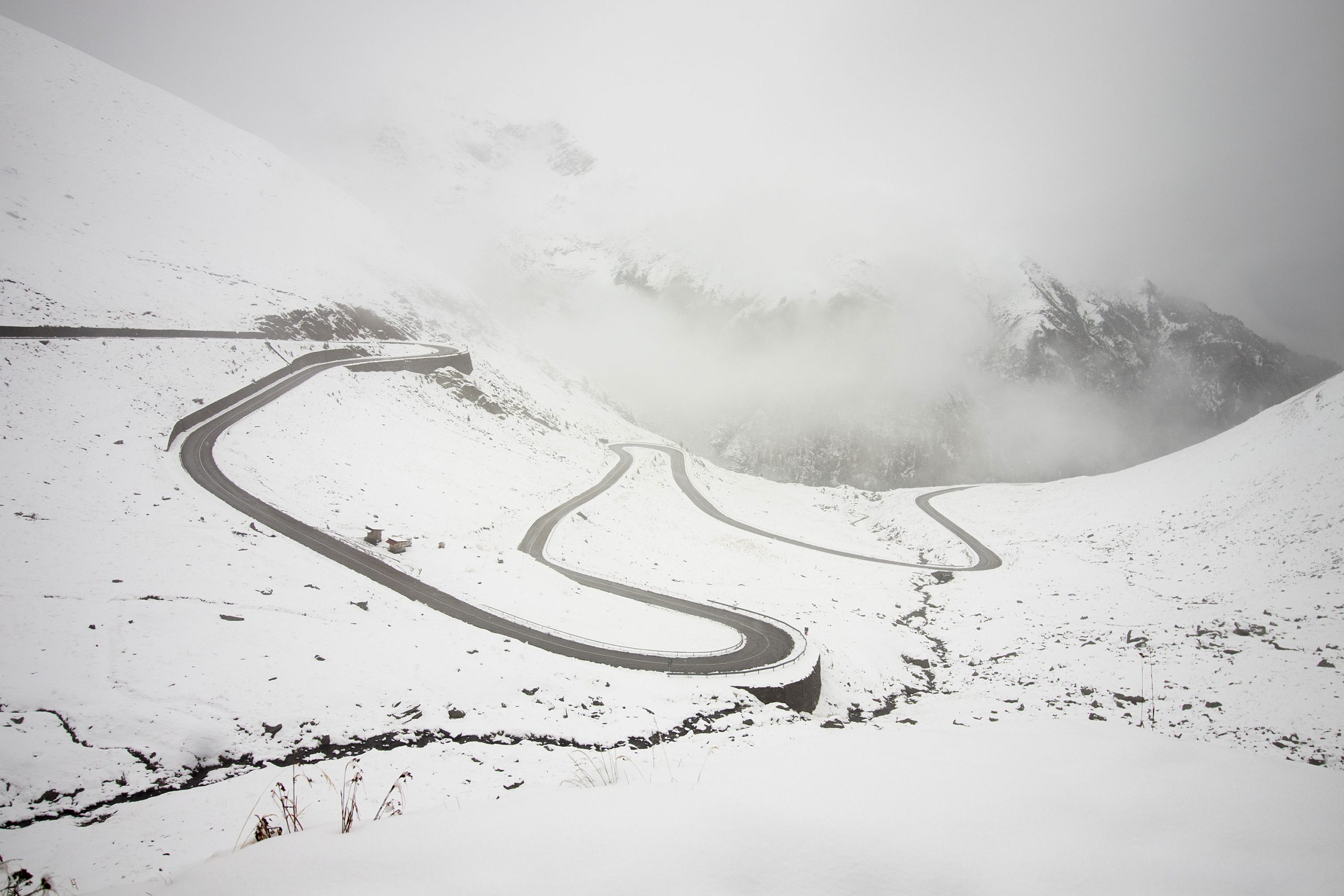 Transfăgărășan_Highway_winding_through_snow_covered_mountains_and_clouds_in_Romania