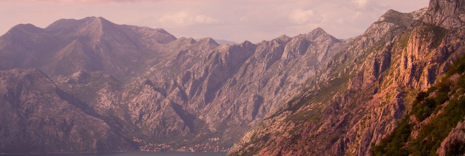 Mountain_coastline_with_dramatic_peaks-and_calm_bay_at_sunset