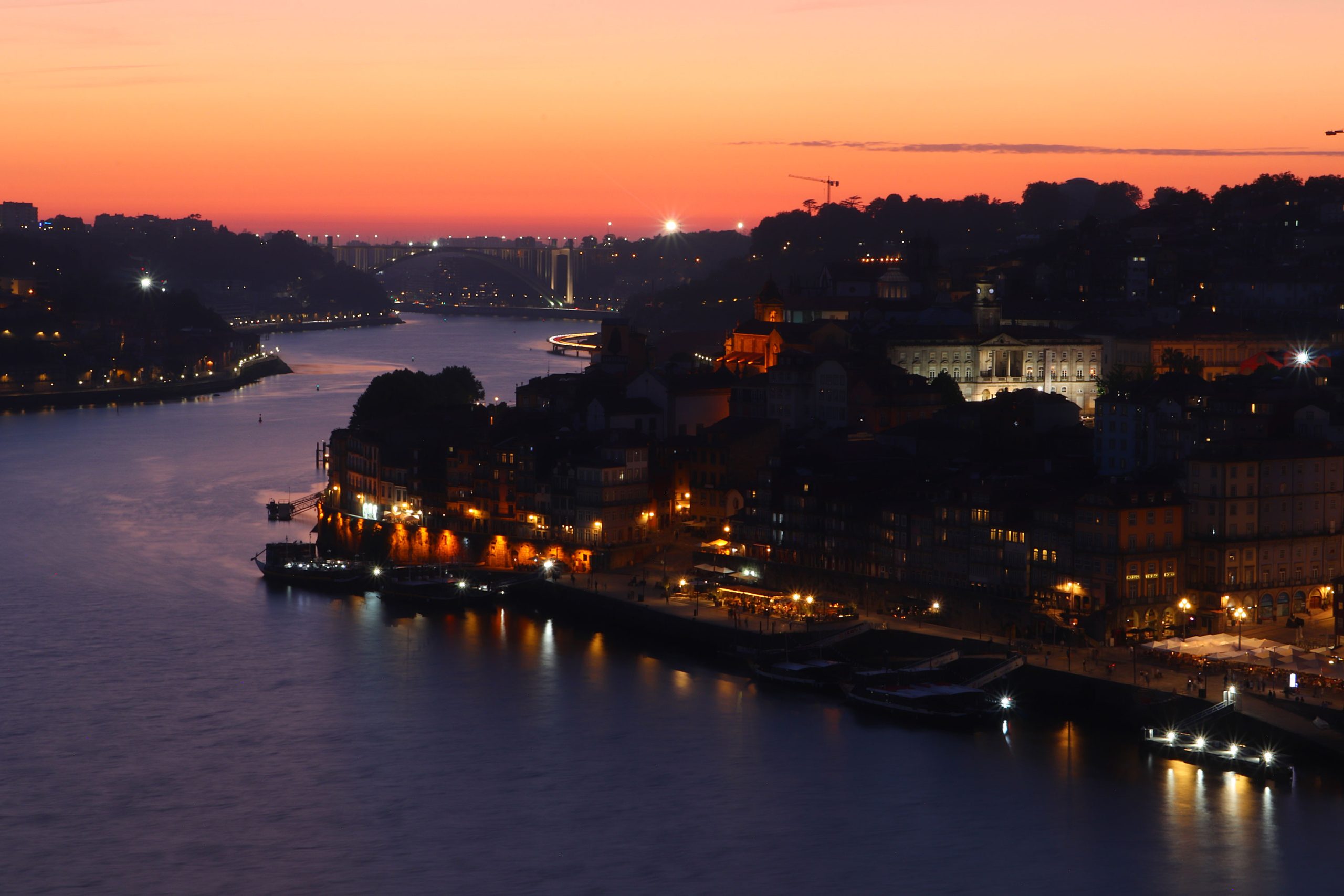 view_over_the_Douro_River_with_Porto's_illuminated_waterfront_and_Arrábida_Bridge_as_sun_sets